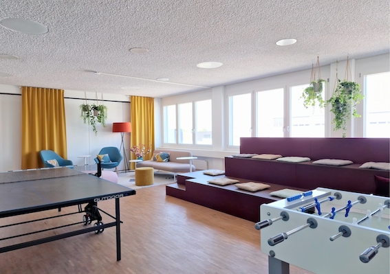 Active Lounge mit einem Tischtennistisch, Fussballkasten, Tribüne und ansprechender Sitzecke für angeregten Austausch im Team.