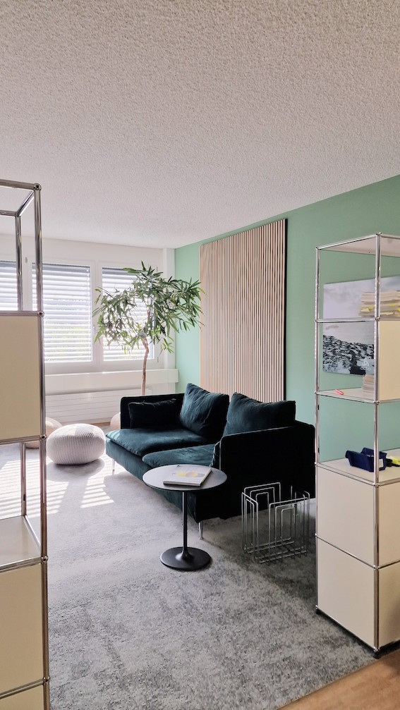 Einladend und modern gestaltetes USM-Buchregal im Büro mit Holzpaneelen, grün-grauem Ambiente von der Natur inspiriert.