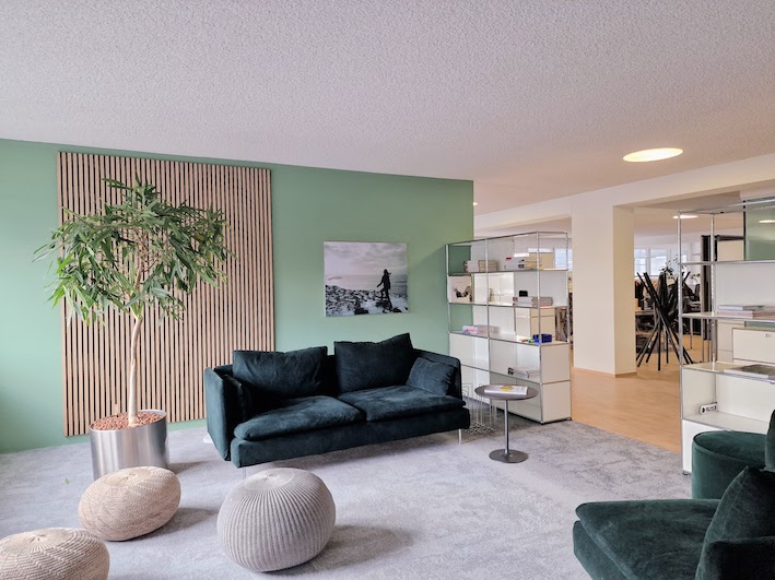 Einladend und modern gestaltetes USM-Buchregal im Büro mit Holzpaneelen, grün-grauem Ambiente von der Natur inspiriert.