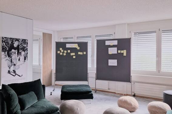 Einladend und modern gestaltetes USM-Buchregal im Büro mit Holzpaneelen, grün-grauem Ambiente von der Natur inspiriert.