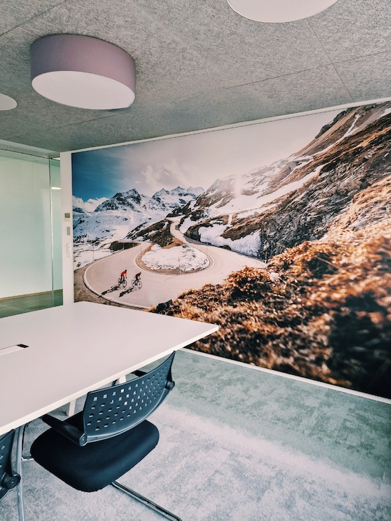 Sitzungszimmer mit XXL-Bild und grün-grauem Fliesenteppich, weisser Vitra Tisch