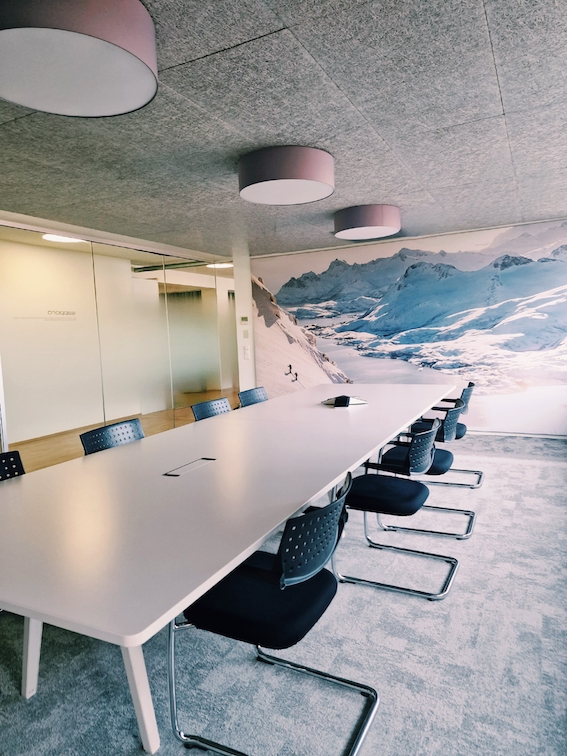 Sitzungszimmer mit XXL-Bild und grün-grauem Fliesenteppich, weisser Vitra Tisch