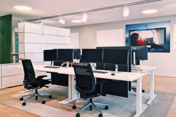 Geräumiger Projektraum mit Whiteboards, höhenverstellbaren Schreibtischen und modernen Drehstühlen für produktives Arbeiten.