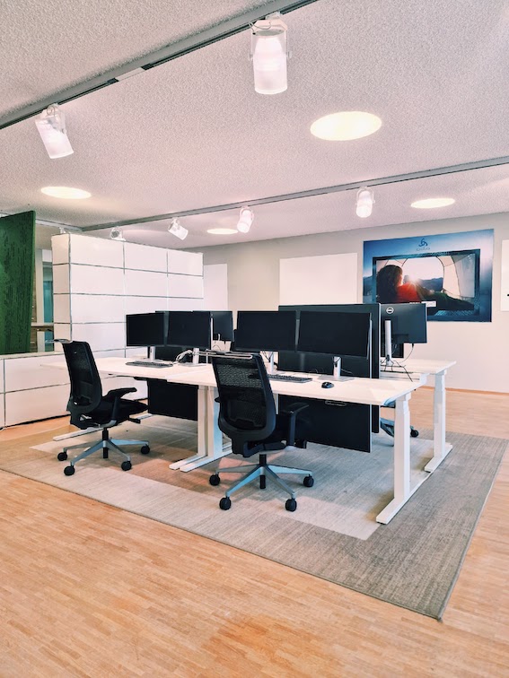 Ger&auml;umiger Projektraum mit Whiteboards, h&ouml;henverstellbaren Schreibtischen und modernen Drehst&uuml;hlen f&uuml;r produktives Arbeiten.