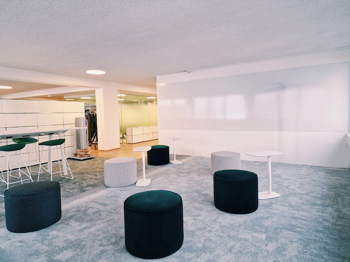 Innovations-Raum mit grauem Interface Teppich, praktischen Laptop-Tischen, grünen und grauen Sitzhocker, Whitewall